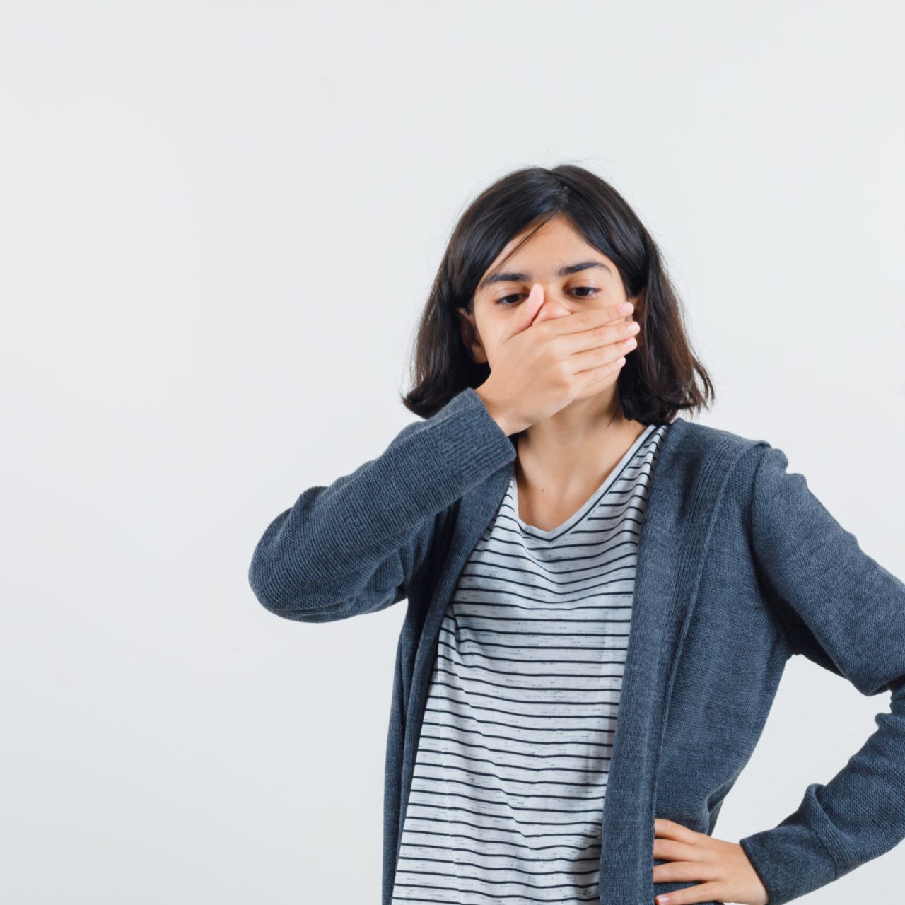 little girl holding hand on mouth in t-shirt, jacket and looking scared. front view.